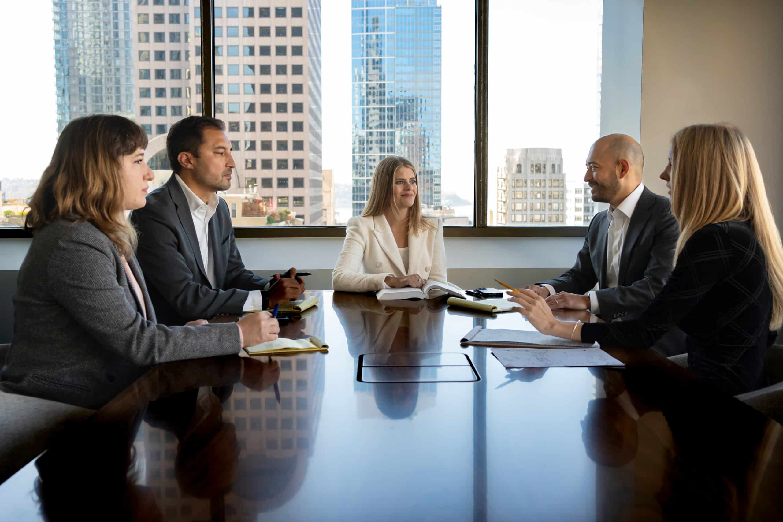 Five asbestos attorneys and partners discuss at a conference table at Oslund Udo Little.
